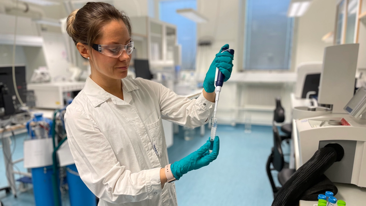 Bild på Zandra Gidlöf i vit labbrock hållande en pipett