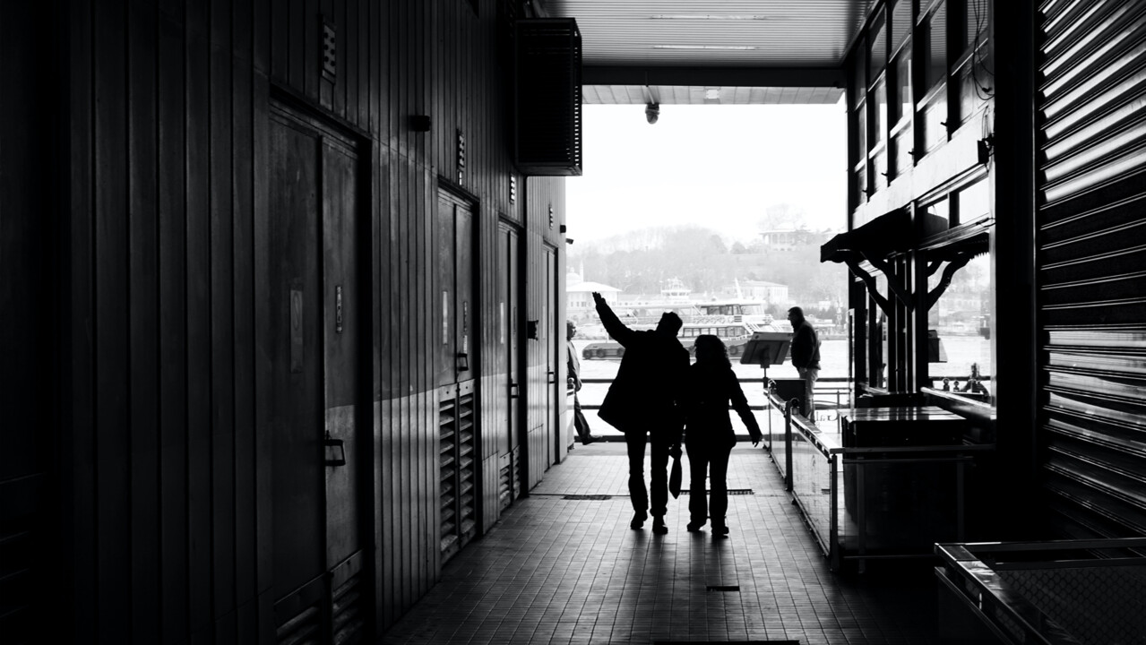 Couple silhouettes walking on narrow passage of modern building_Furkanfdemir